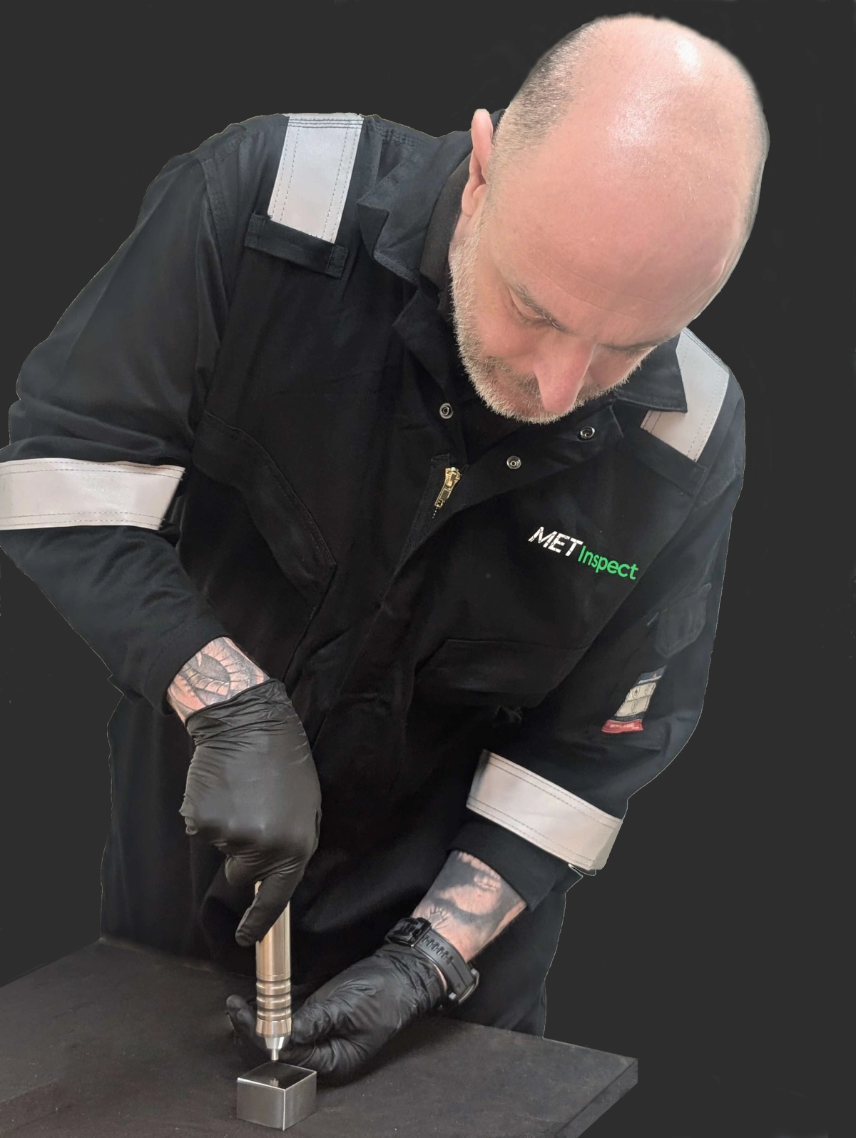 A metallurgy technician performing on-site hardness testing on a steel component using the Ultrasonic Contact Impedance (UCI) method.